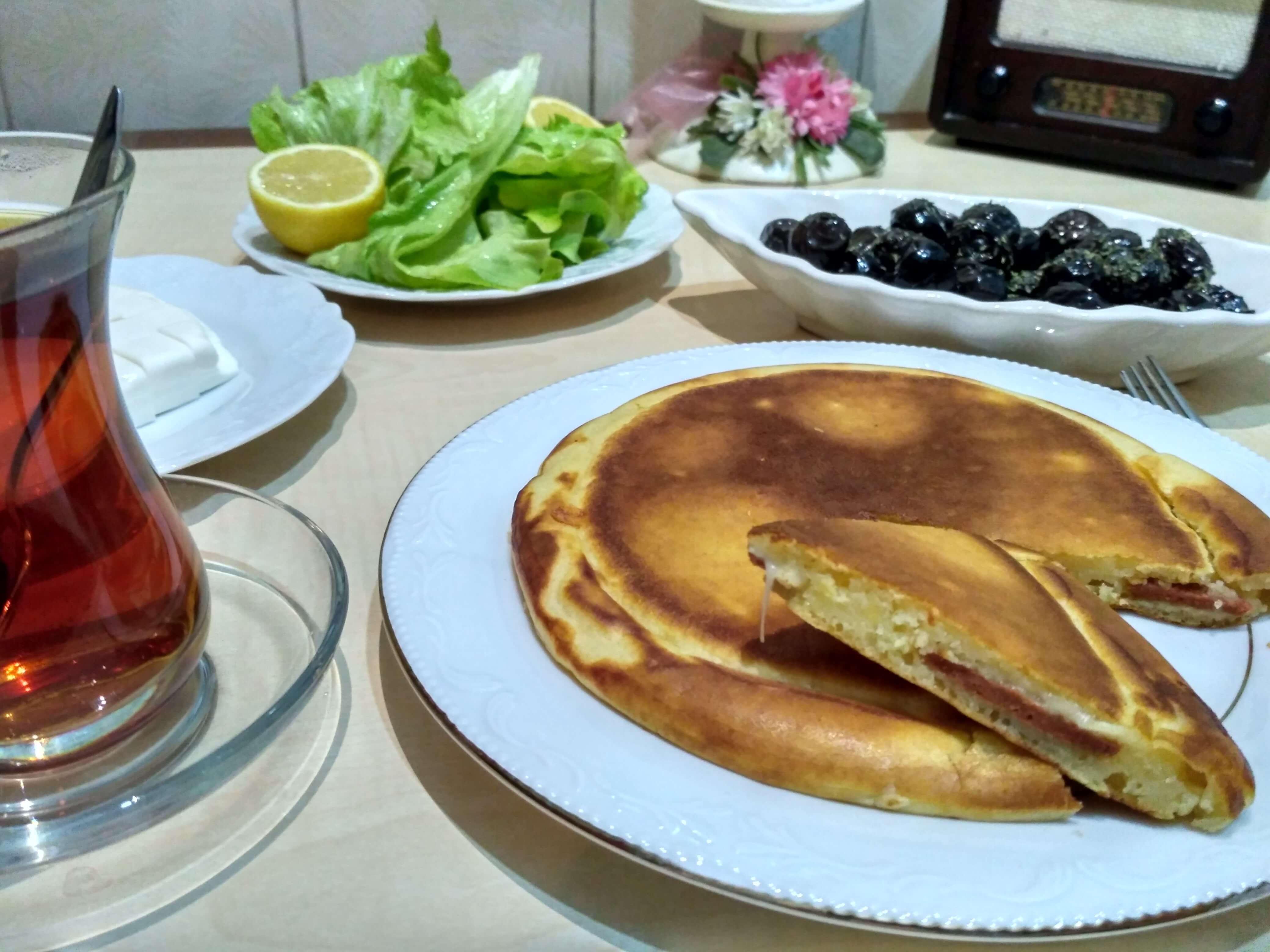 Kahvaltılık sucuklu krep, eriyen kaşar peyniri ve lezzetli sucuk dilimleriyle servis ediliyor.