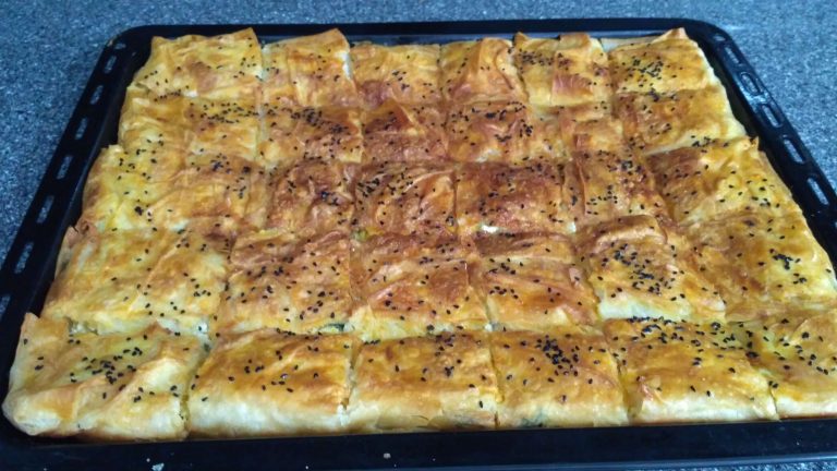 Hazır yufkadan peynirli börek tarifi: Tepsiye dizilmiş yufkalar ve iç harcı eklenmiş, fırına girmeye hazır börek.