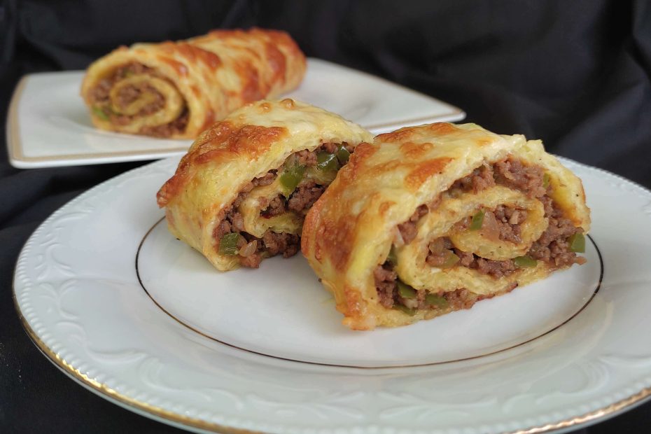 Fırından yeni çıkmış kıymalı rulo patates yemeği, üzerine erimiş kaşar peyniri eklenmiş.