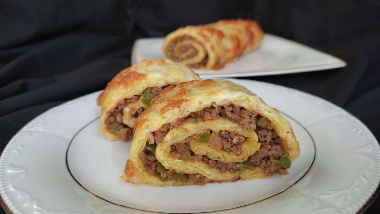 Kıymalı rulo patates, dilimlenmiş ve servis tabağına alınmış halde, yanında yoğurtlu sos.