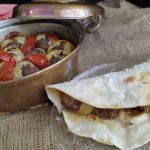 Pişmiş soğan kebabı, yanında közlenmiş domates ve biber ile servis ediliyor.