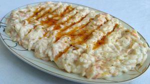 Yoğurtlu şehriye salatası, ceviz ve nane ile süslenmiş halde.