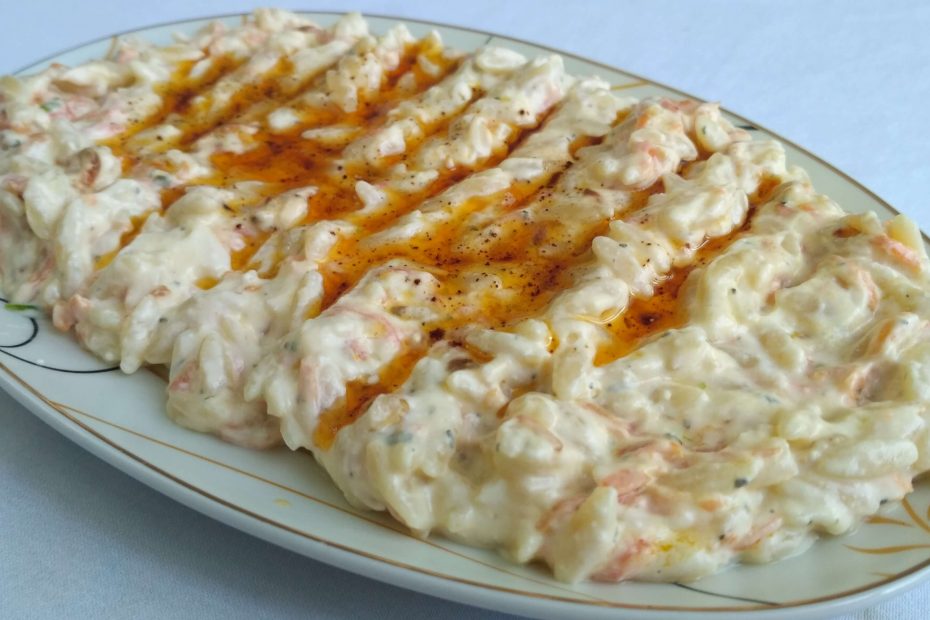 Yoğurtlu şehriye salatası, ceviz ve nane ile süslenmiş halde.